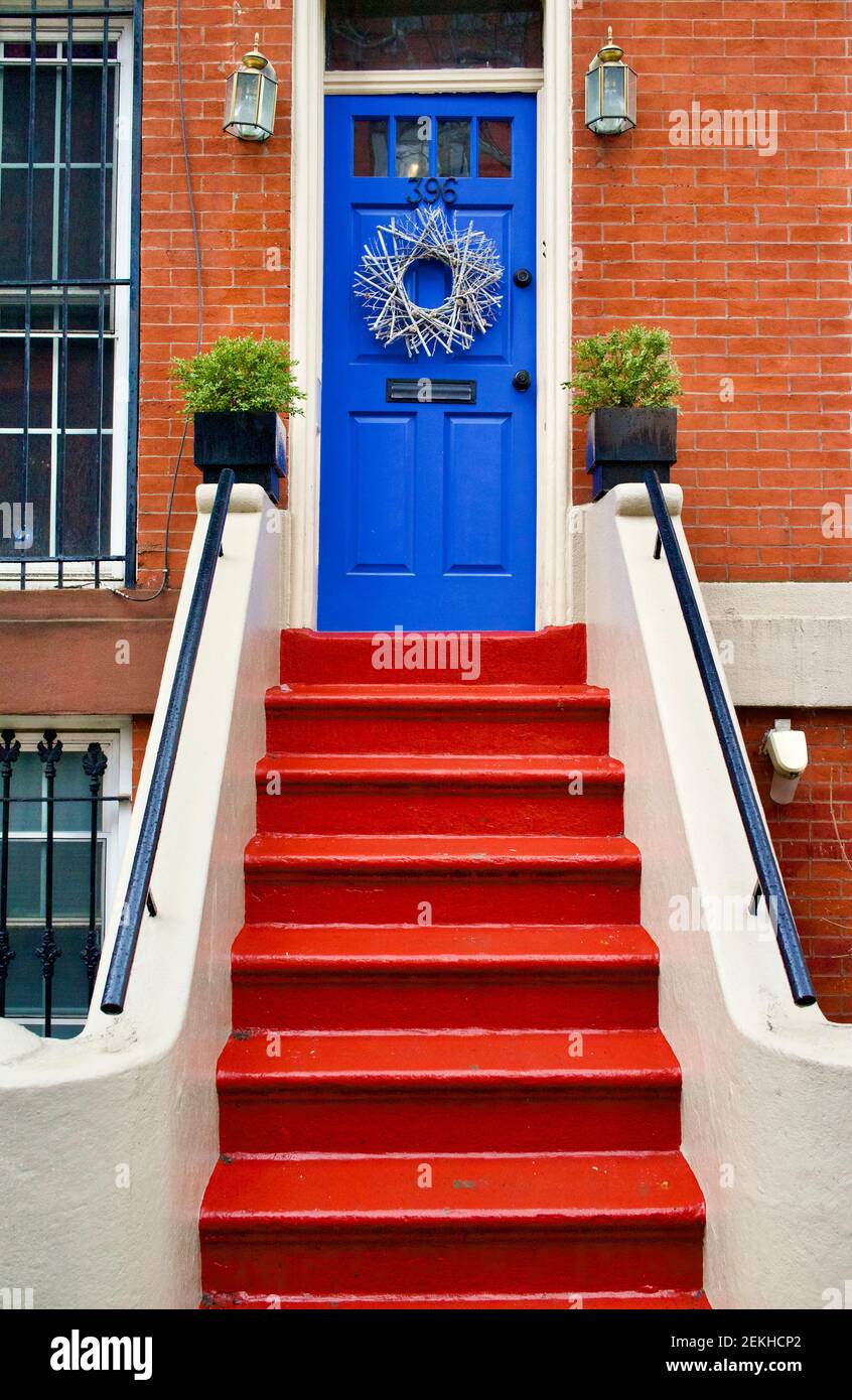 Blue front door on brick brownstone in Brooklyn, New York, NYC, USA. Red painted steps lead up