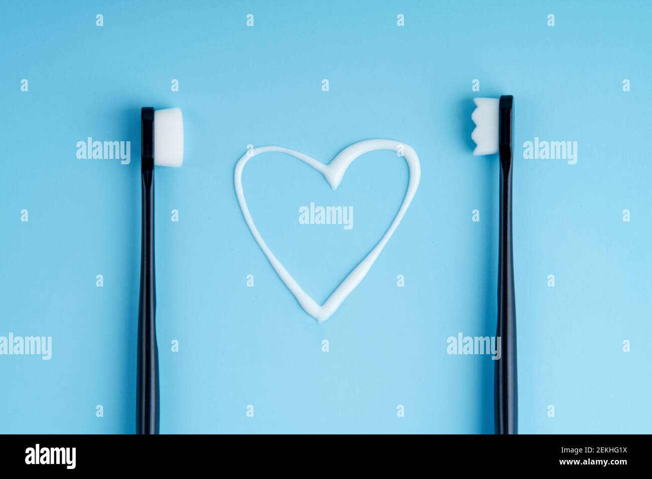 Heart shaped toothpaste between two toothbrushes. Stock Photo