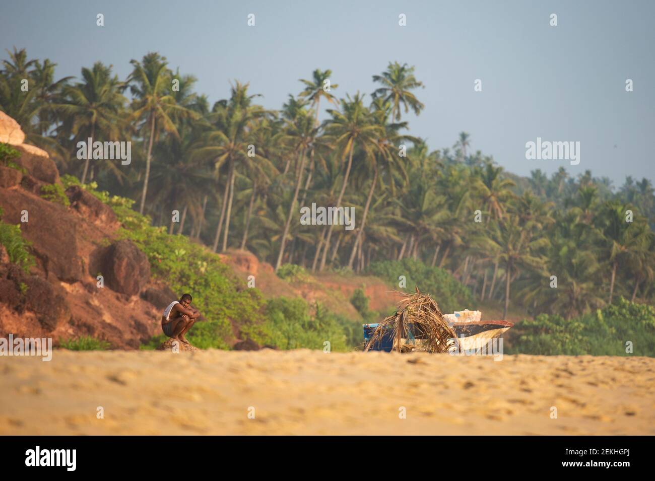 An Indian man is sitting on a beach during sunset. A man unemployed due to the Covid-19 pandemic, Varkala, Kerala, India. Stock Photo