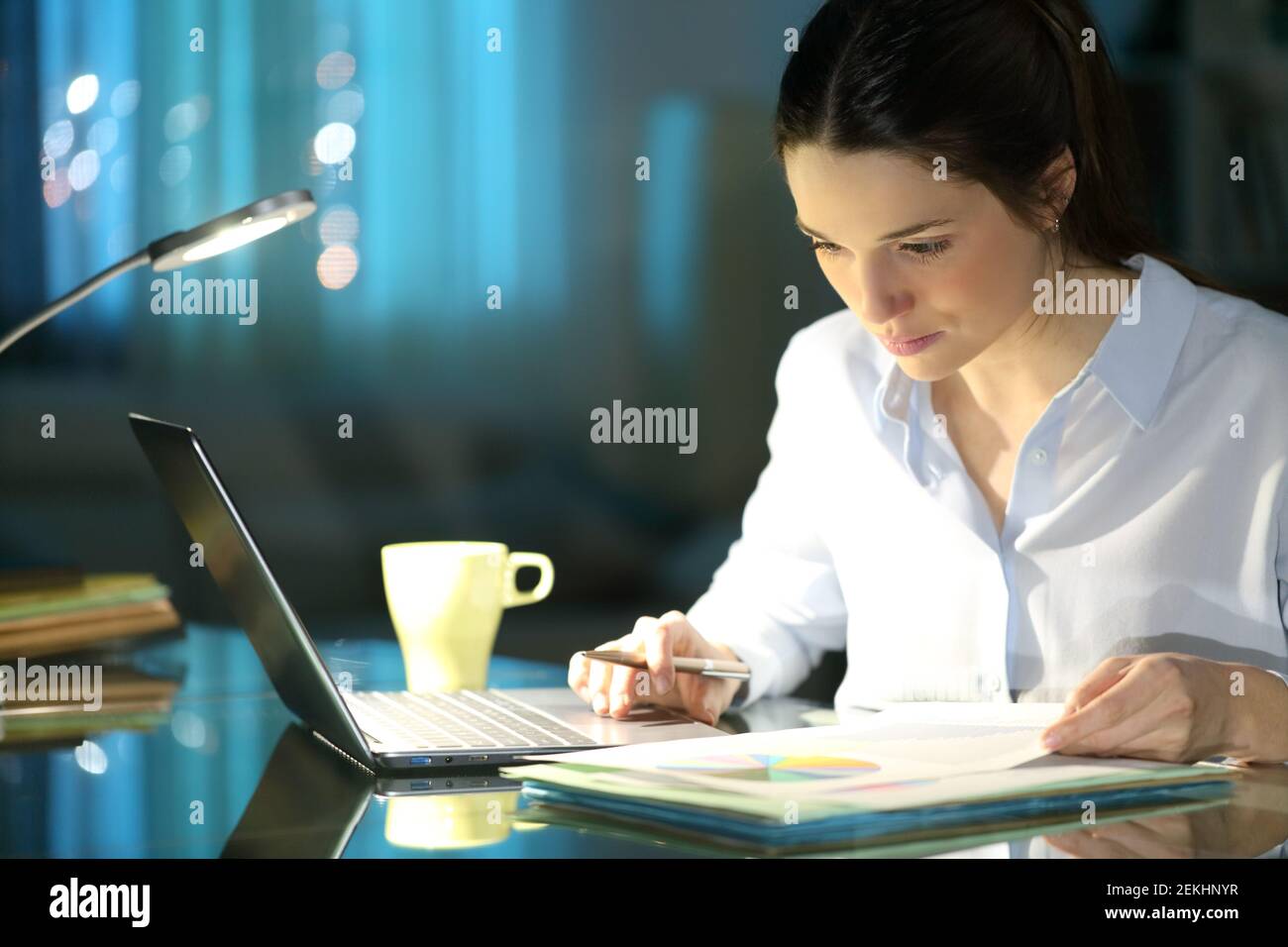 Businesswoman comparing inform on laptop working in the night at homeoffice Stock Photo