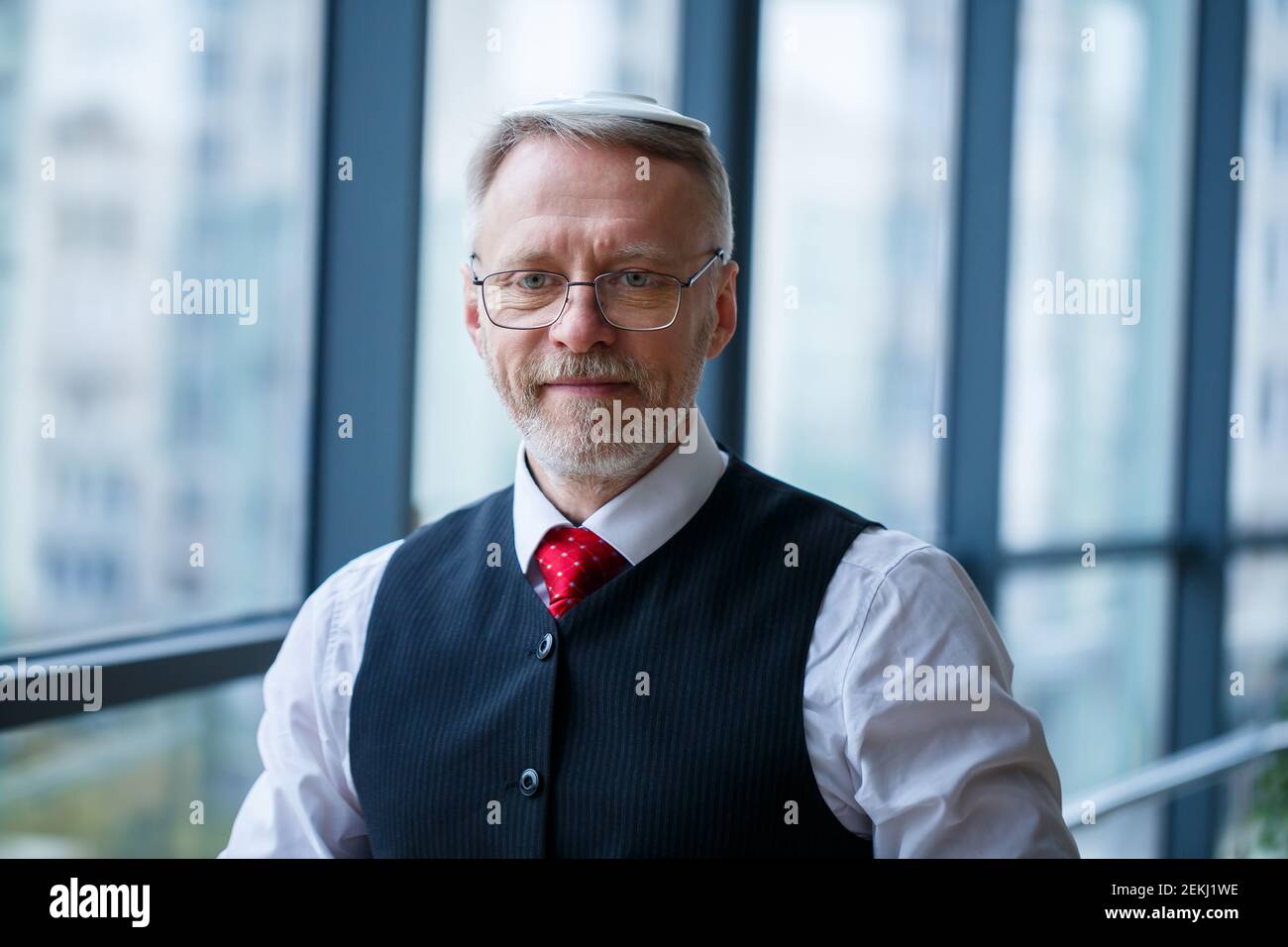 Smiling happy managing director thinks about his successful career development while stands in his office near the background of a window with copy sp Stock Photo