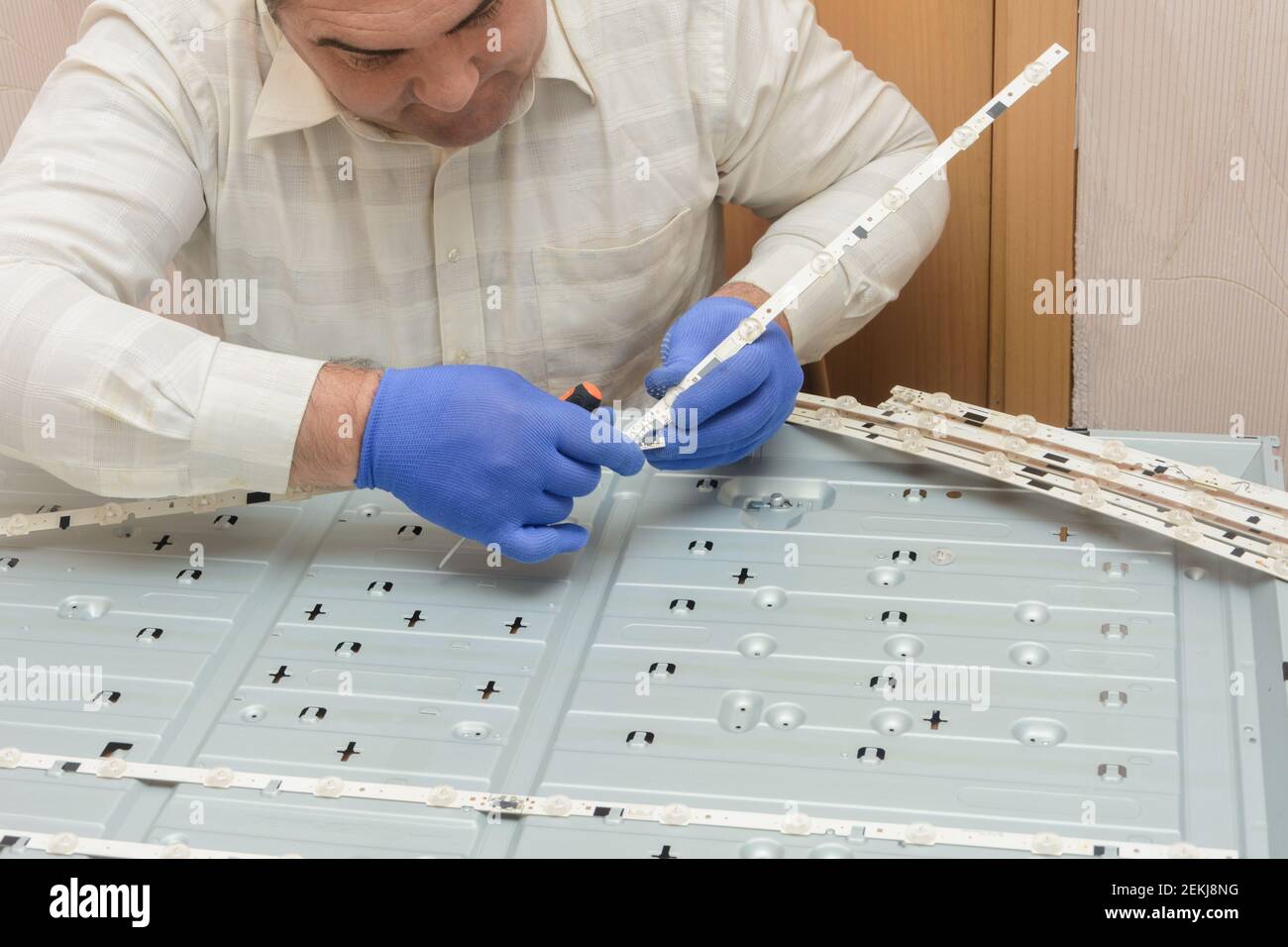 Repair of LCD TV in service center. Master removes LED strips with lamps from monitor case. Stock Photo