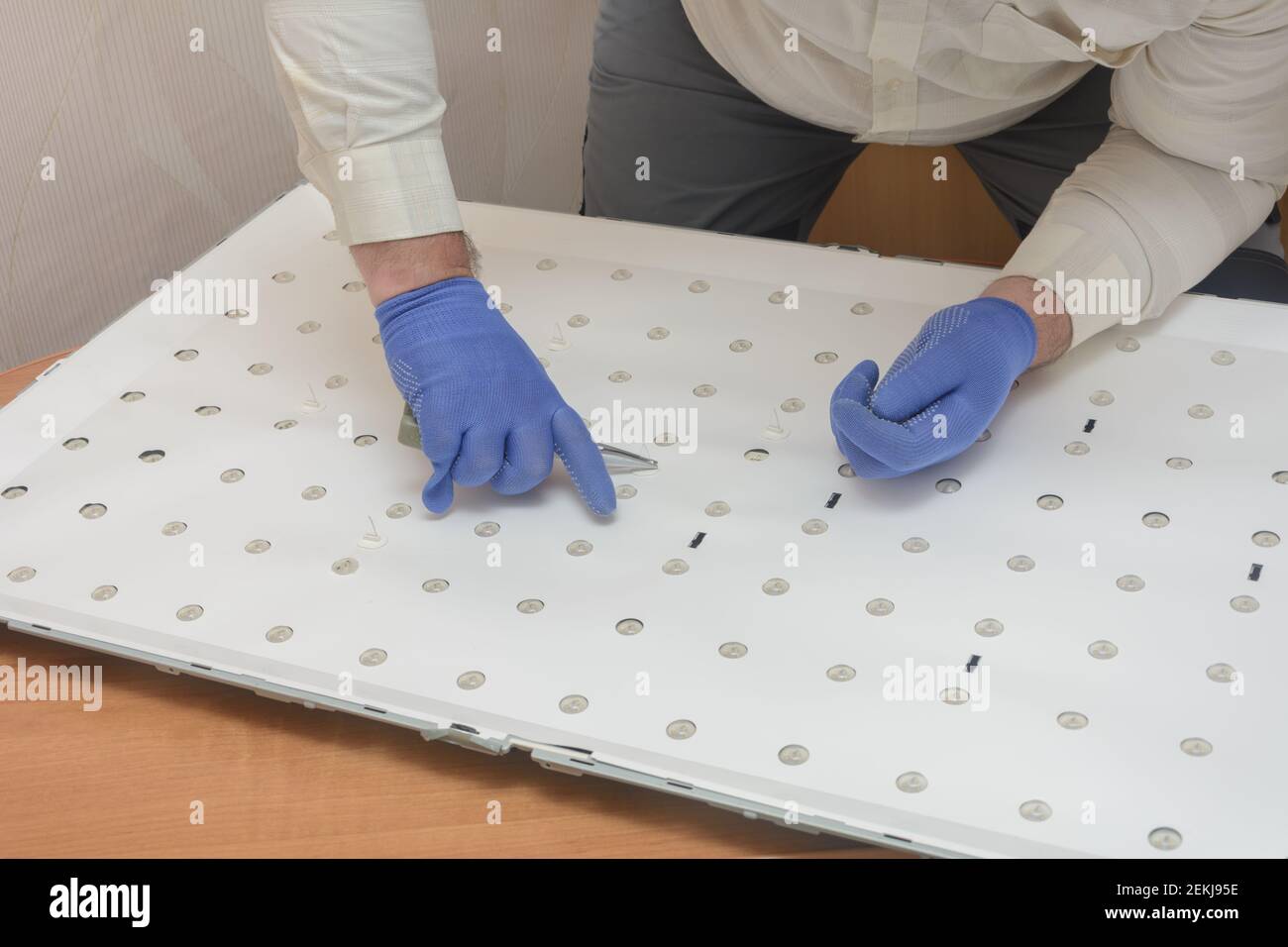 Disassembled panel of large LCD TV in service center. Technician removes LED lighting for repair. Debugg. Stock Photo