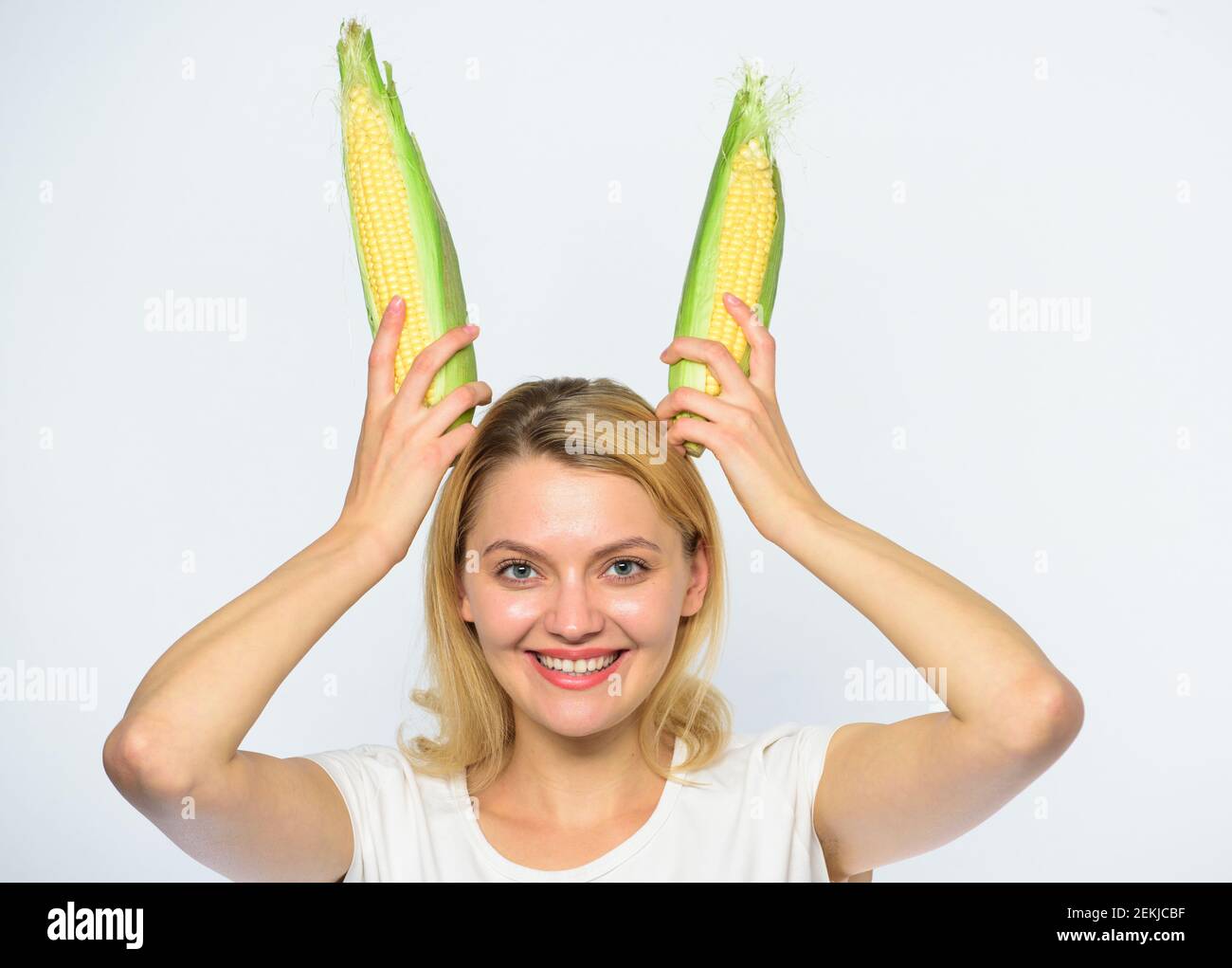 Vegetarian nutrition concept. Woman hold yellow corn cob on white