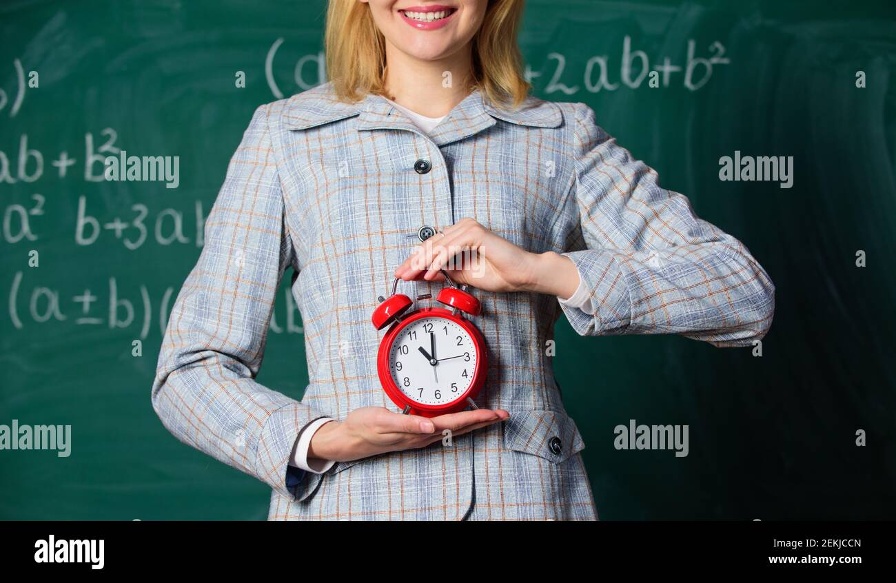 Teachers attributes. Alarm clock in hands of teacher or educator