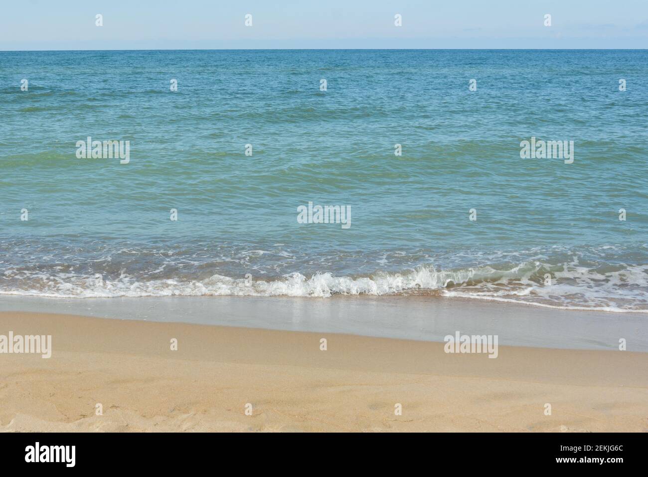 Beautiful sandy beach and soft wave with white foam, sea surf. Natural background for summer vacation. Stock Photo