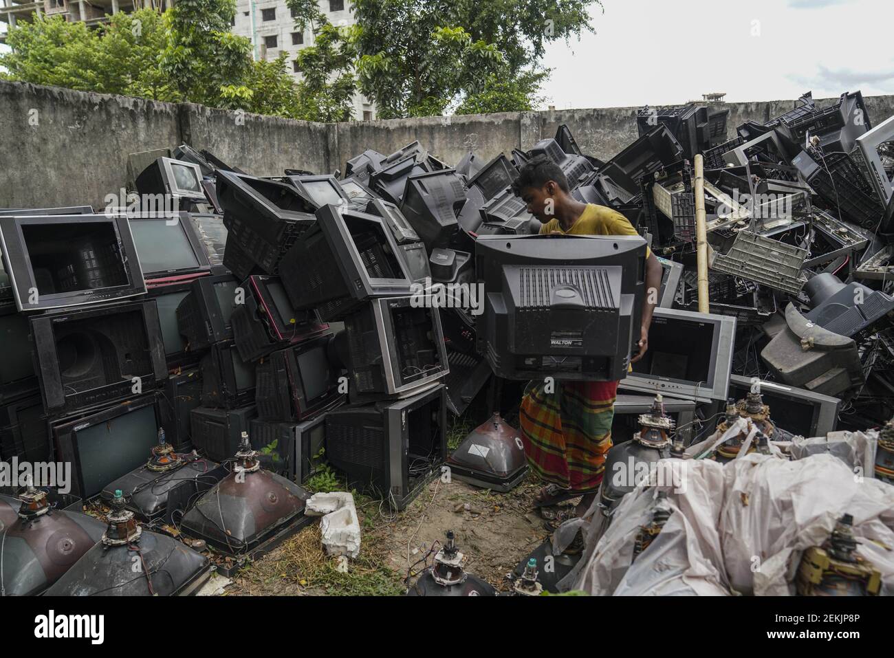 A man is seen sorting TVs for recycle at a TV recycling scrap yard in Dhaka. (Photo by Zabed