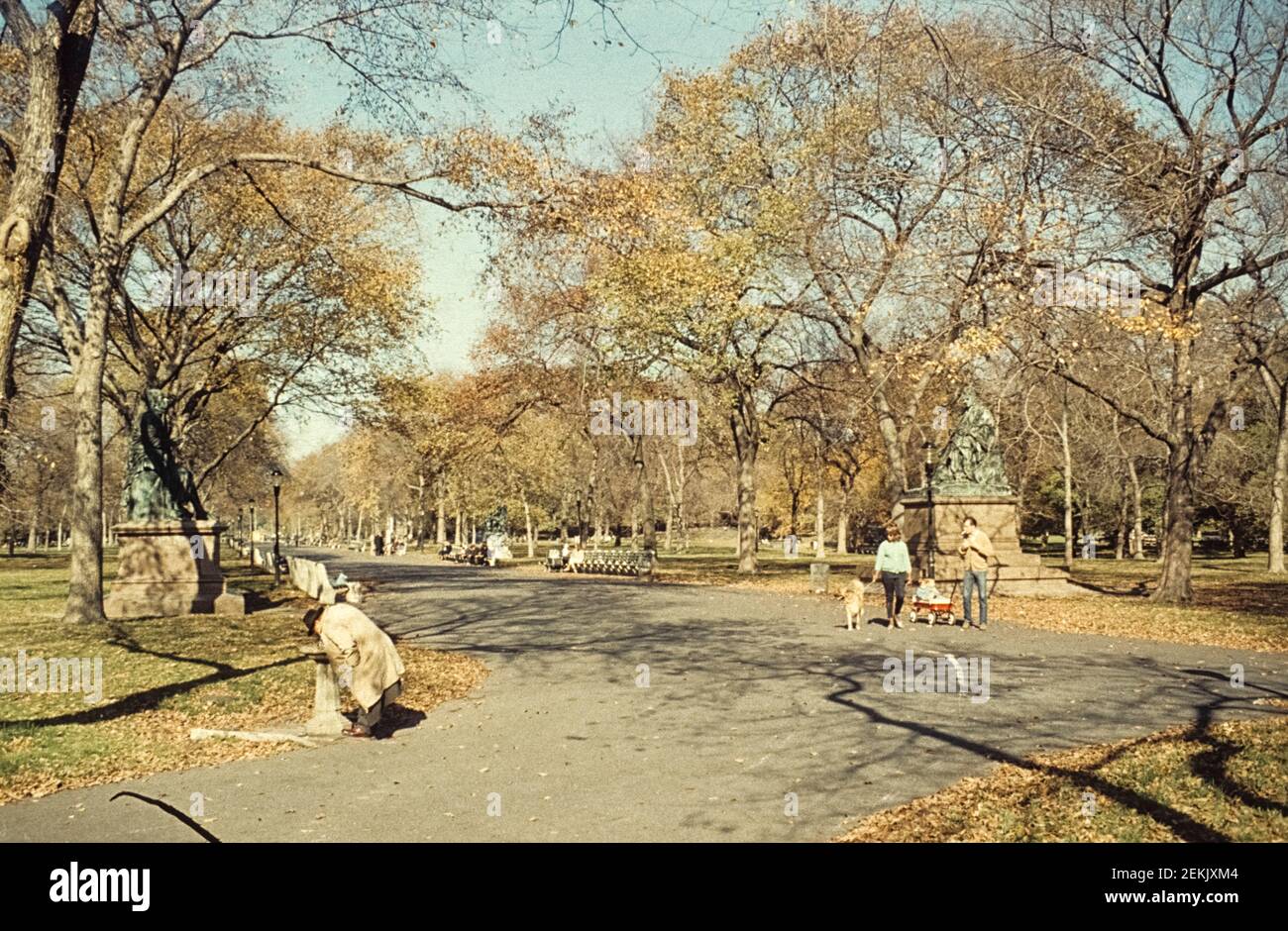 Few people are on the way. A man is drinking from a fountain. A familiy goes for a walk. Literary Walk, Manhattan, Central Park, New York City, 1965 Stock Photo