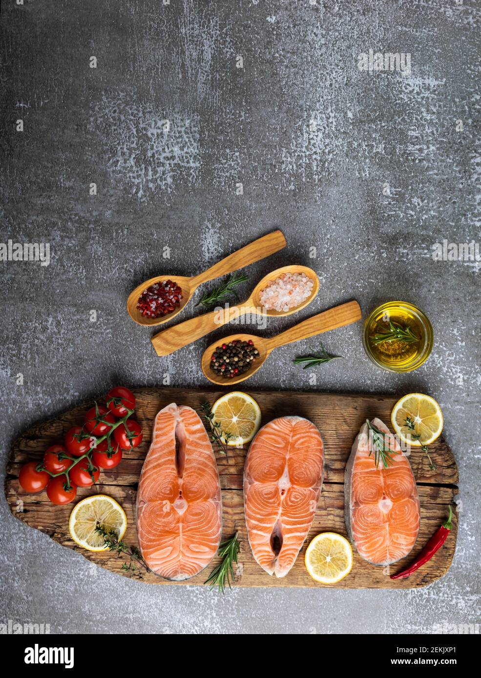 three raw steak fish trout, salmon and spices on wooden board, dark background Stock Photo