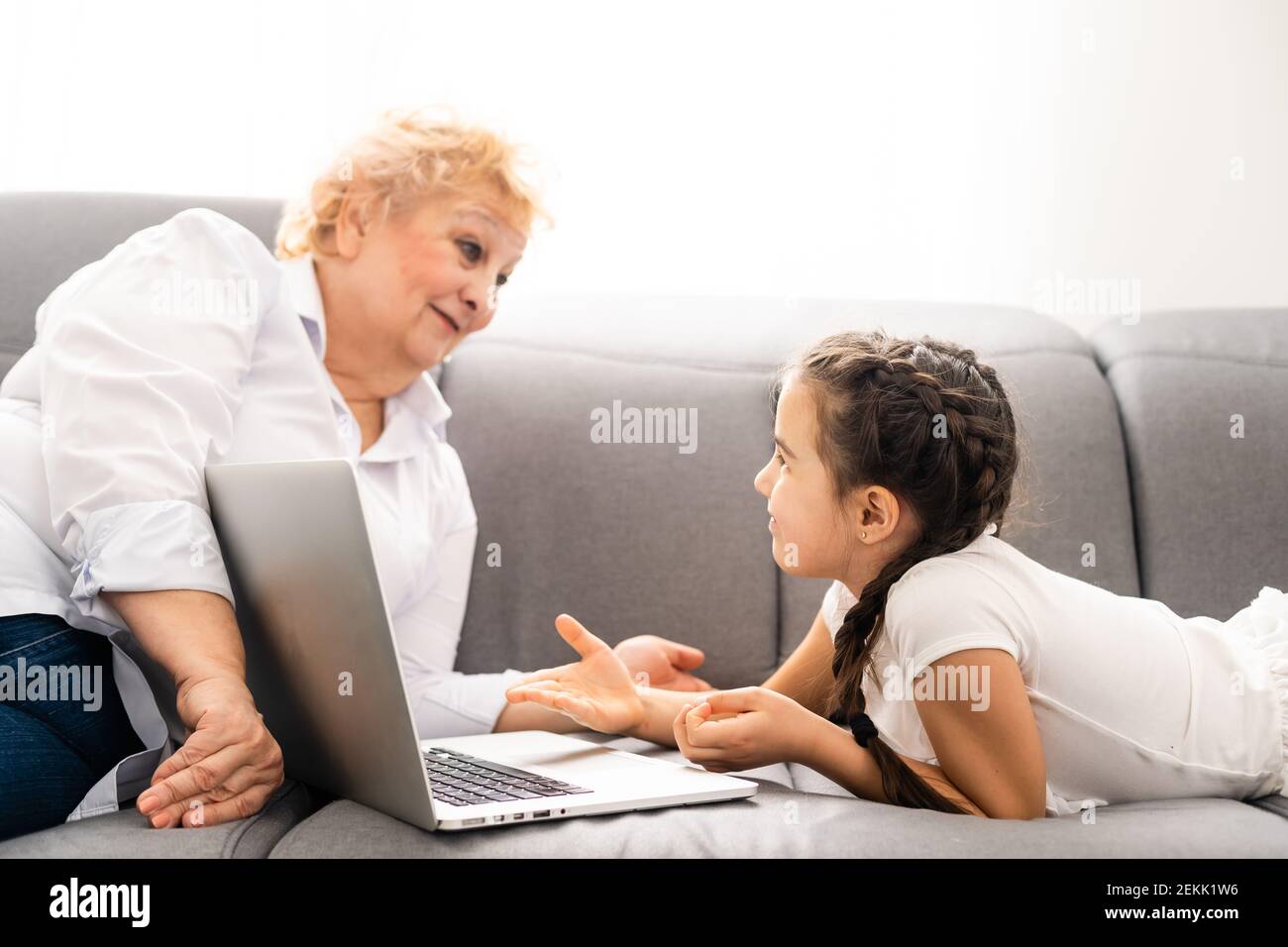 modern grandmother teaching grandchild how to use laptop computer at