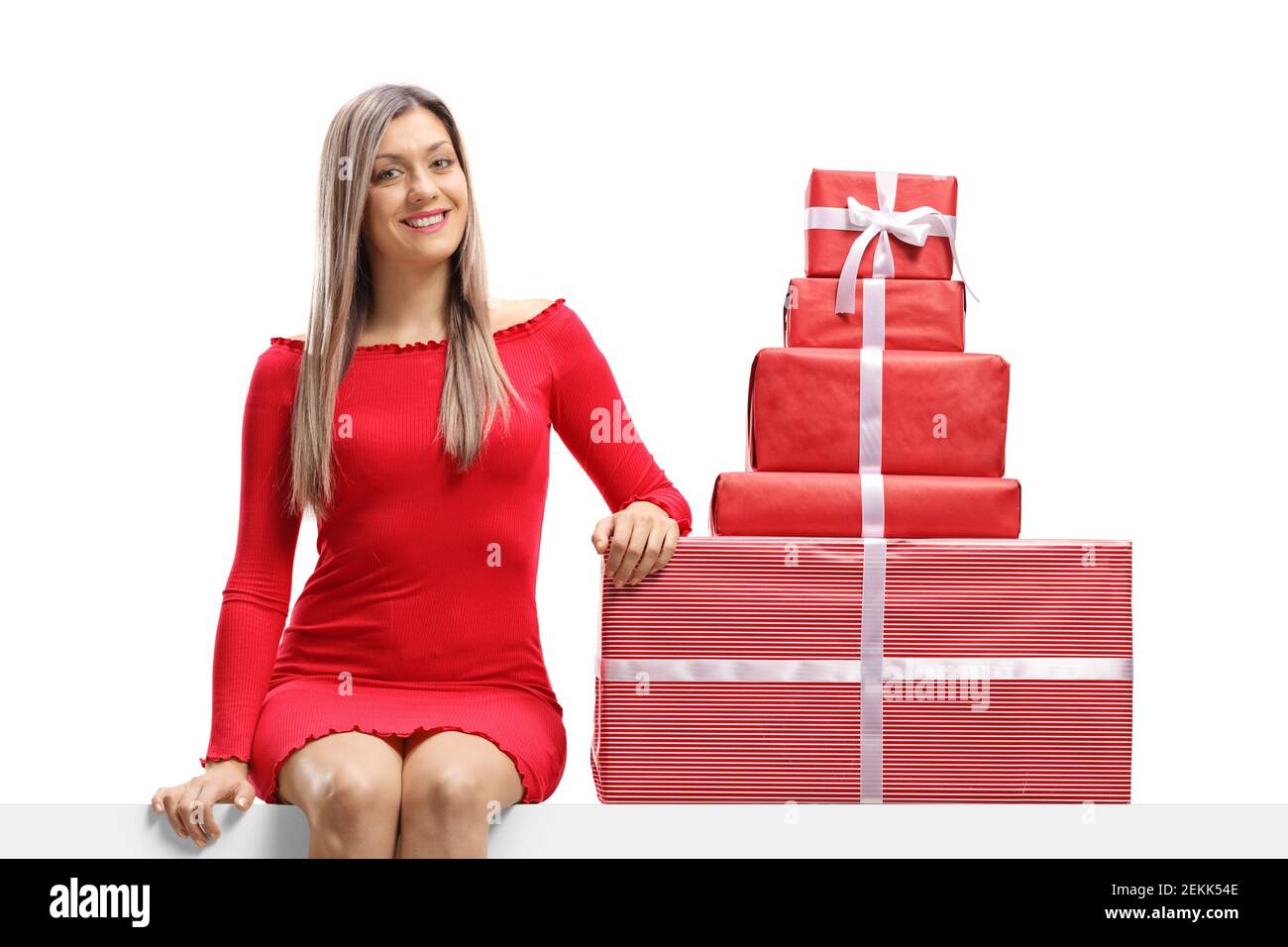 Woman in a mini red dress sitting on a panel with presents isolated on ...