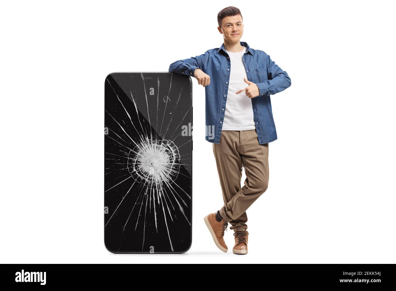 Full length portrait of a guy leaning on a big mobile phone with a broken screen and pointing isolated on white background Stock Photo