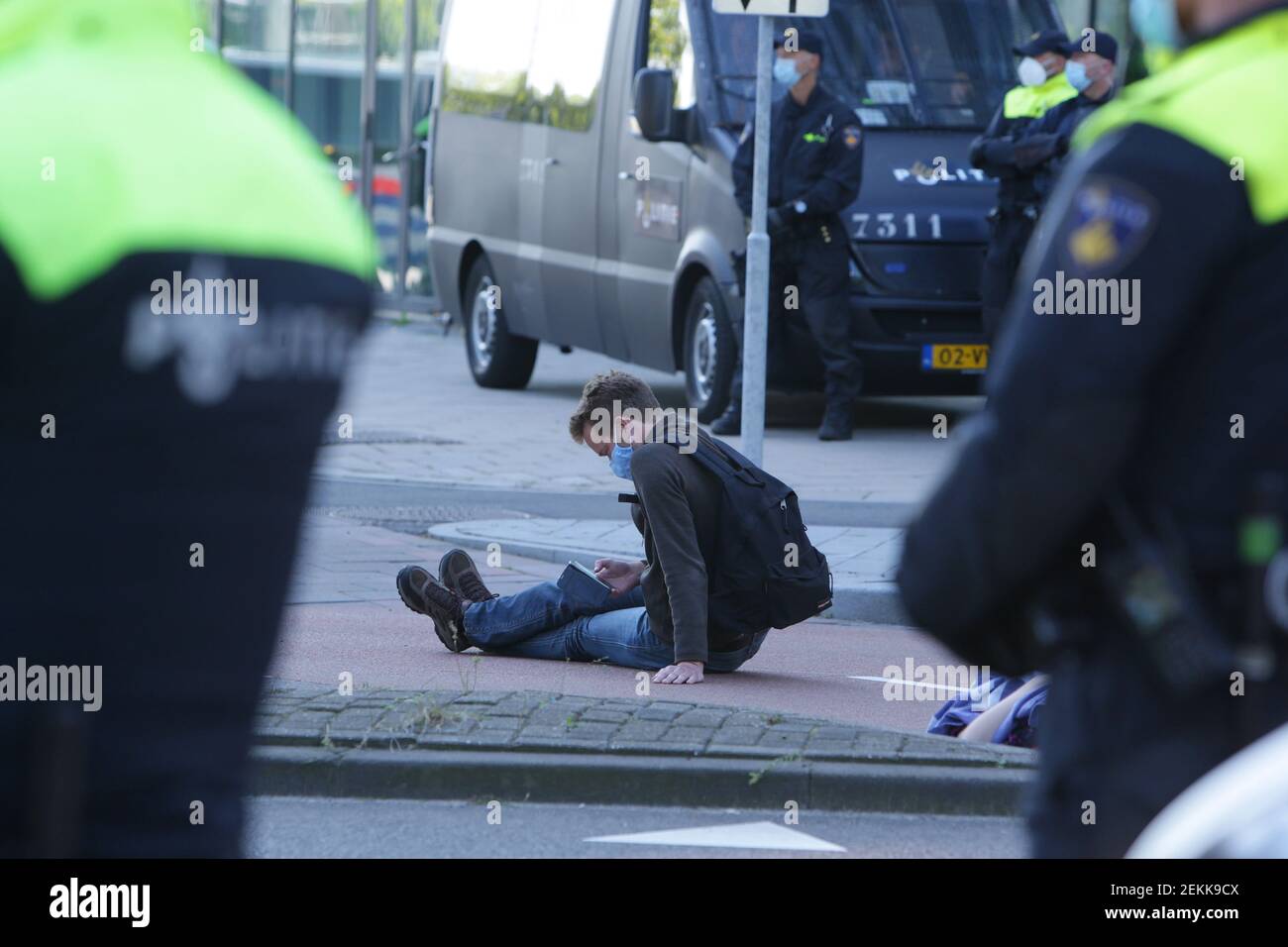 Dutch police officers watch an Extinction Rebellion activist glues his