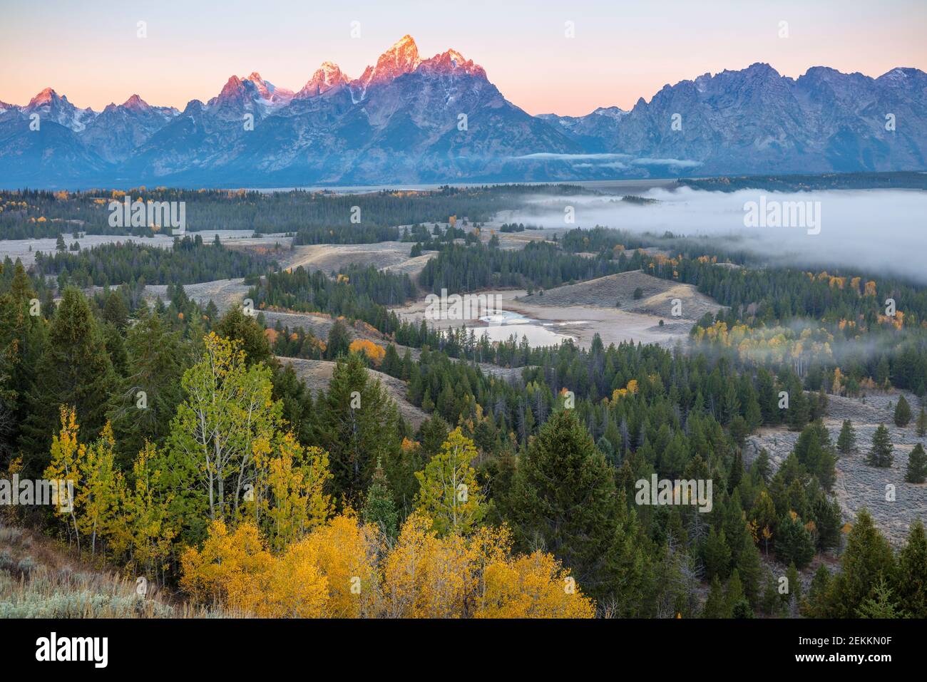 Grand Teton National Park, WY: Sunrise light on the Teton Range with fog in the Snake River Valley in fall Stock Photo