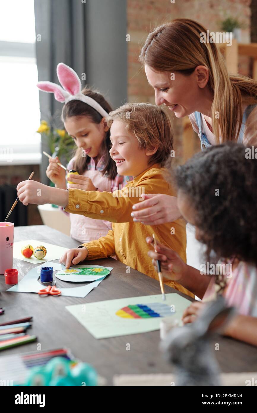 Group of children learning to paint pictures together with teacher