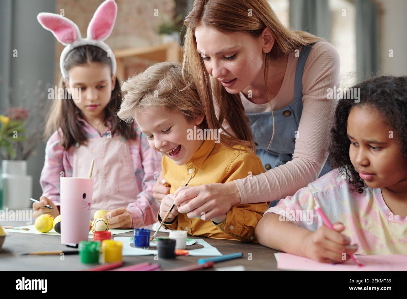 Group of children sitting at the table and painting pictures with ...