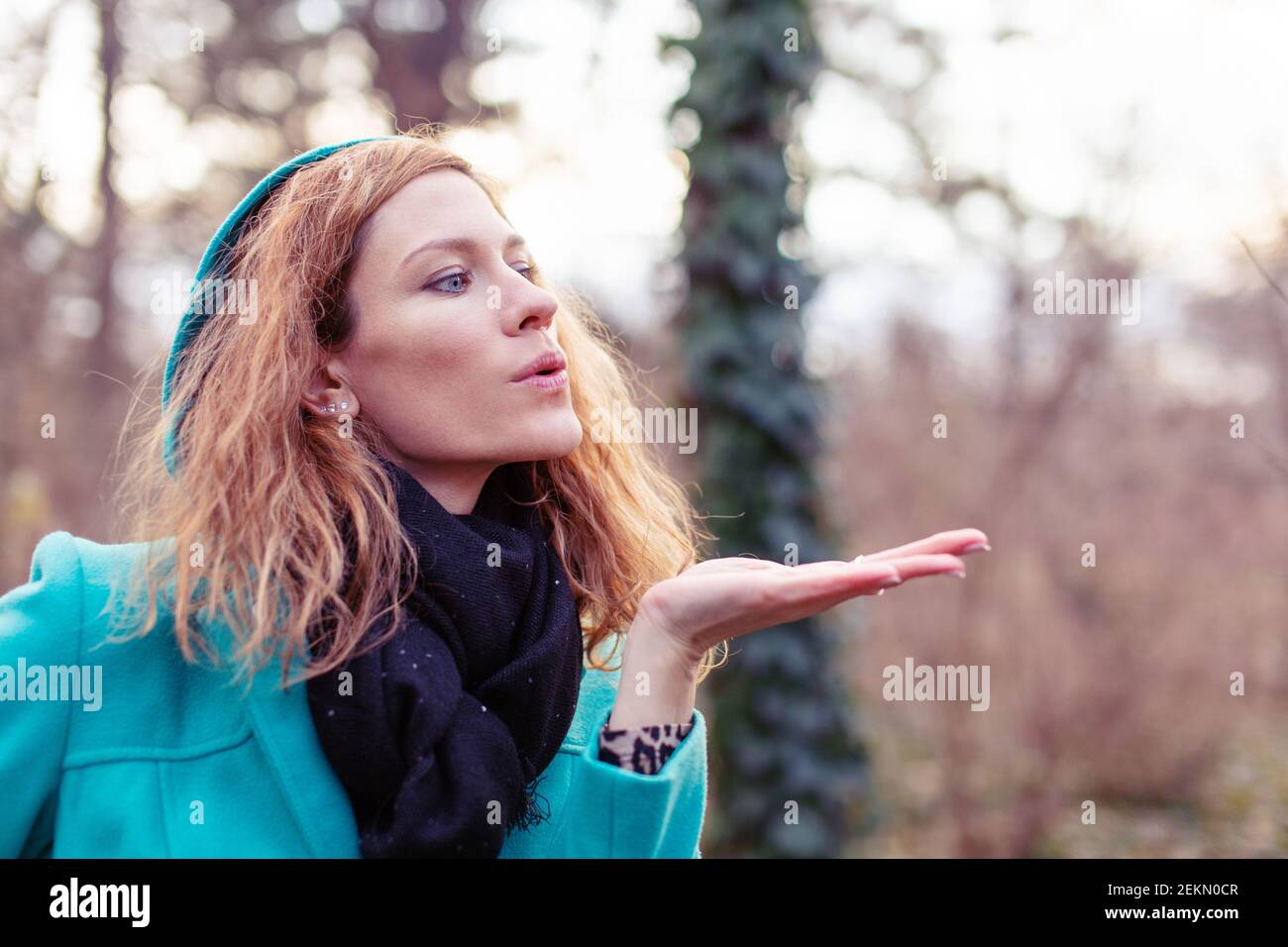 Young redhead Caucasian woman sending kisses at early spring Stock Photo