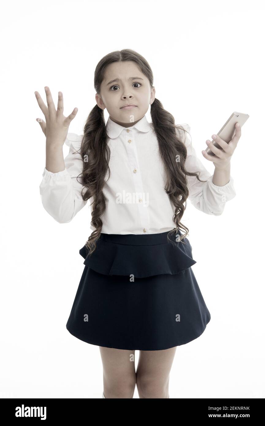 Girl cute long curly hair holds smartphone white background. Child desperate helpless face expression holds smartphone. Chatting friends online communication. Bad connection. Cell connection problem. Stock Photo