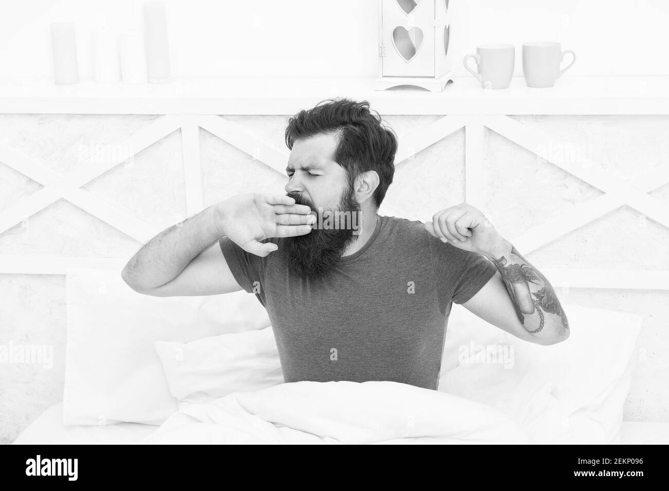 pleasant bed time routine. brutal male spending time in room. relax lifestyle concept. bearded man yawn in bed. wake up at morning. bachelor feel comfortable. yawning guy at bedroom. lazy sunday. Stock Photo