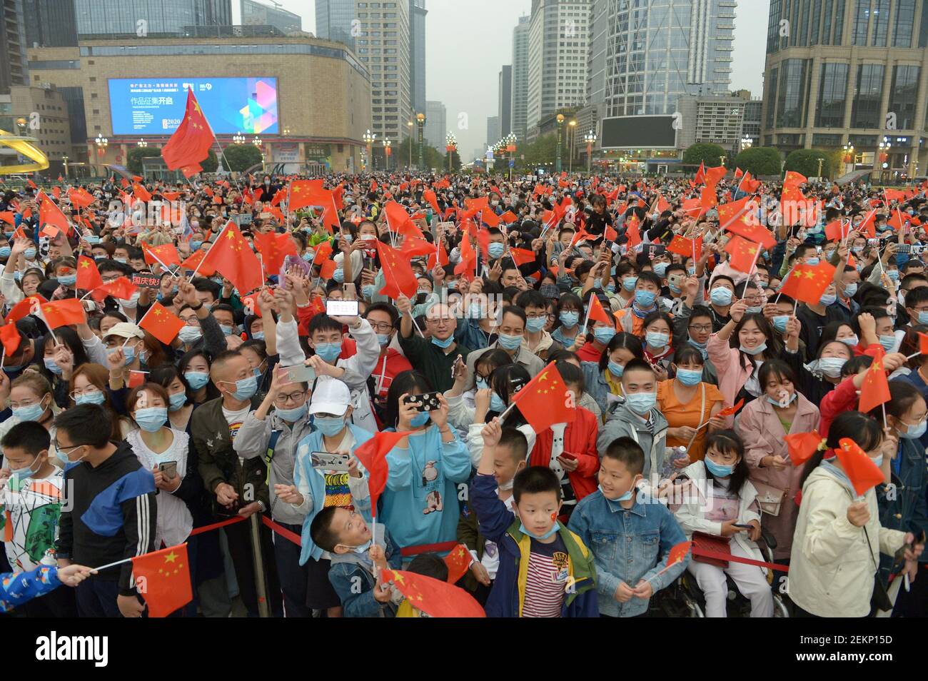 People wave Chinese flags while watching the Chinese flag raising ...