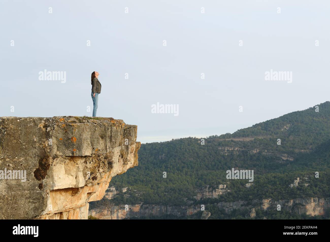 Full body portrait of a woman breathing fresh air in the top of a cliff in the mountain Stock Photo