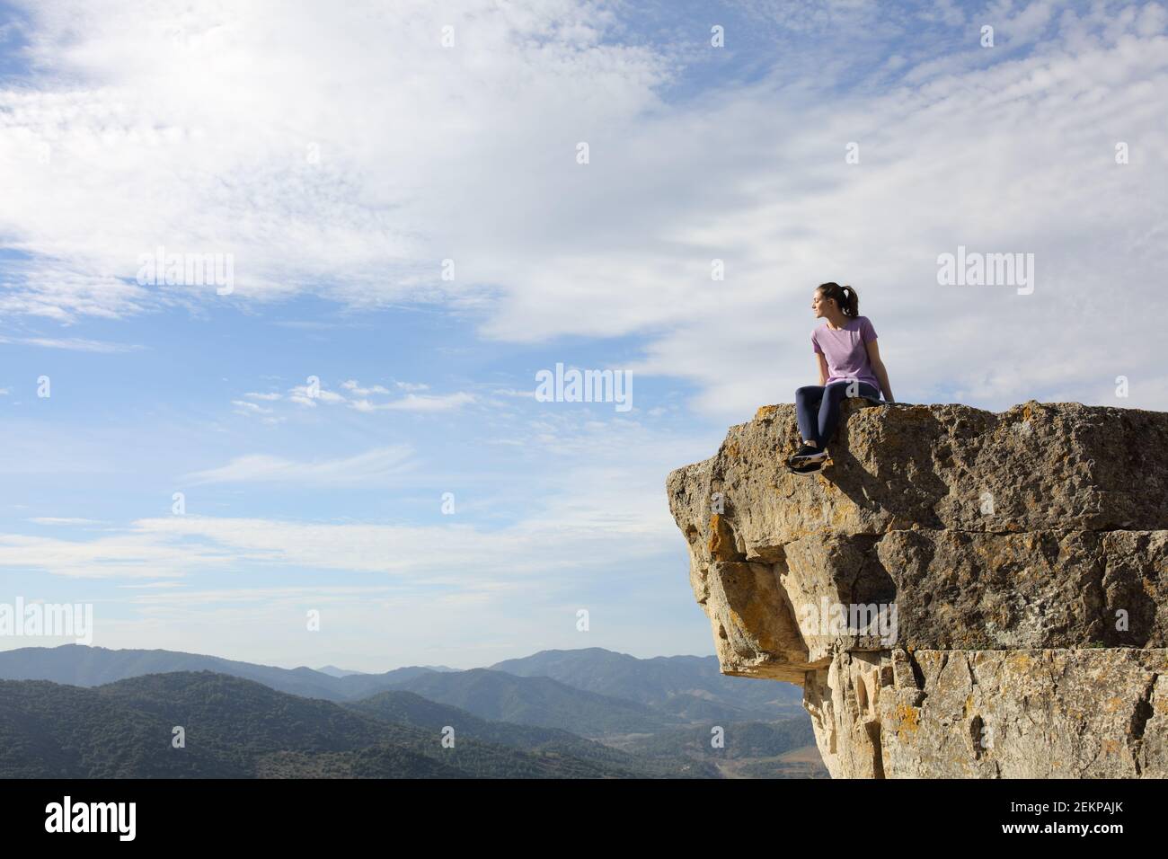 Runner resting sitting contemplating views from the top of a cliff in the mountain Stock Photo