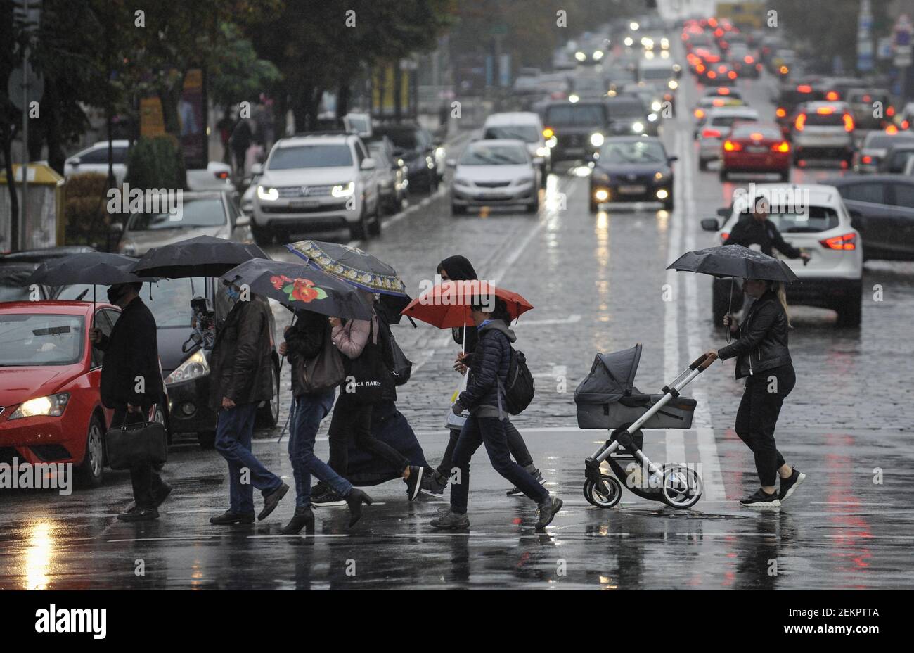 People using umbrellas cross the street on a rainy day. (Photo by ...
