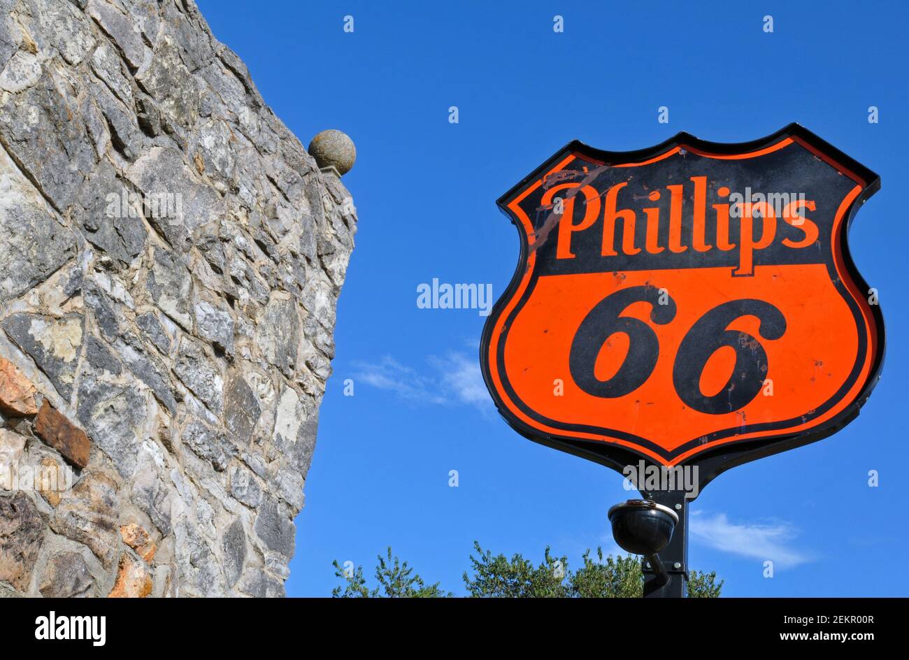 An old Phillips 66 sign stands beside the former stone service station