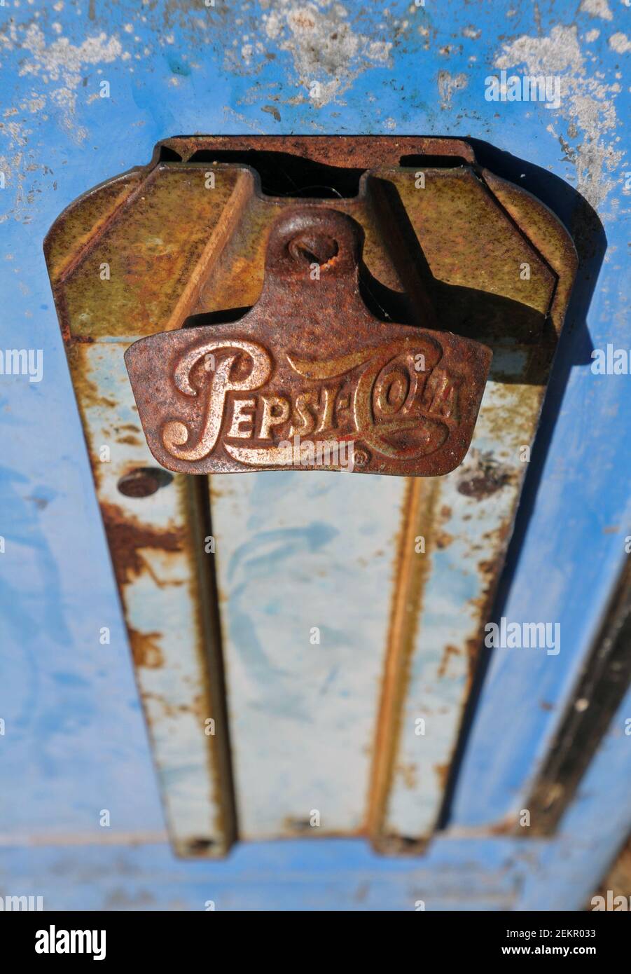 Detail of a rusted metal bottle opener attached to a vintage Pepsi-Cola beverage cooler in Spencer, Missouri. Stock Photo