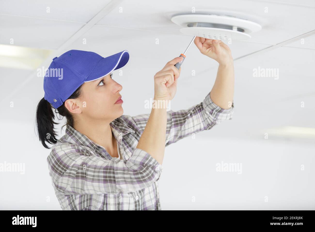 female worker screwing something in the ceiling Stock Photo - Alamy