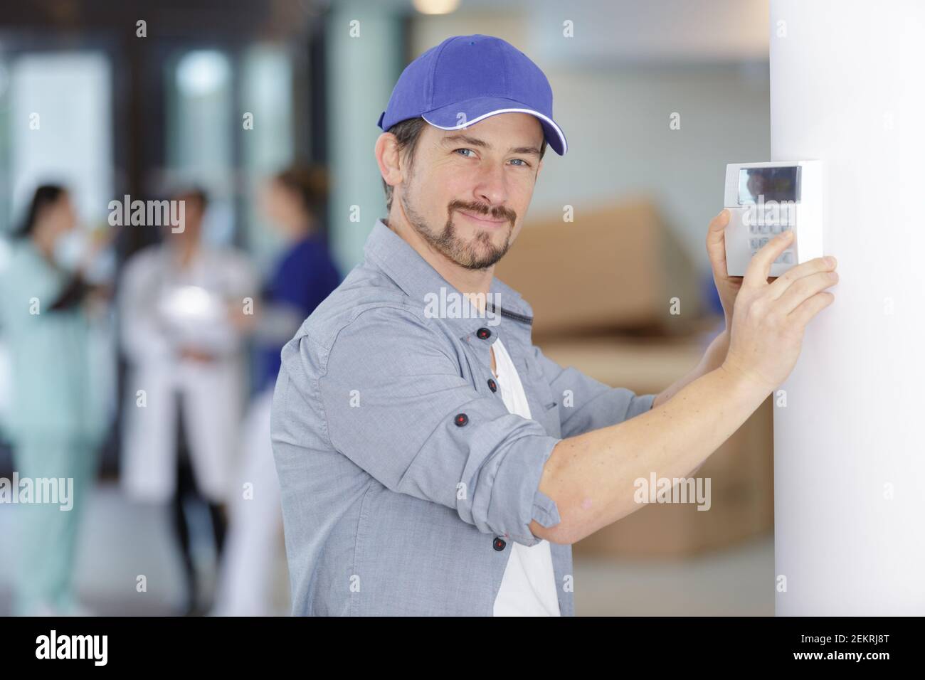trained hvac technician checking troubleshooting a thermostat Stock Photo