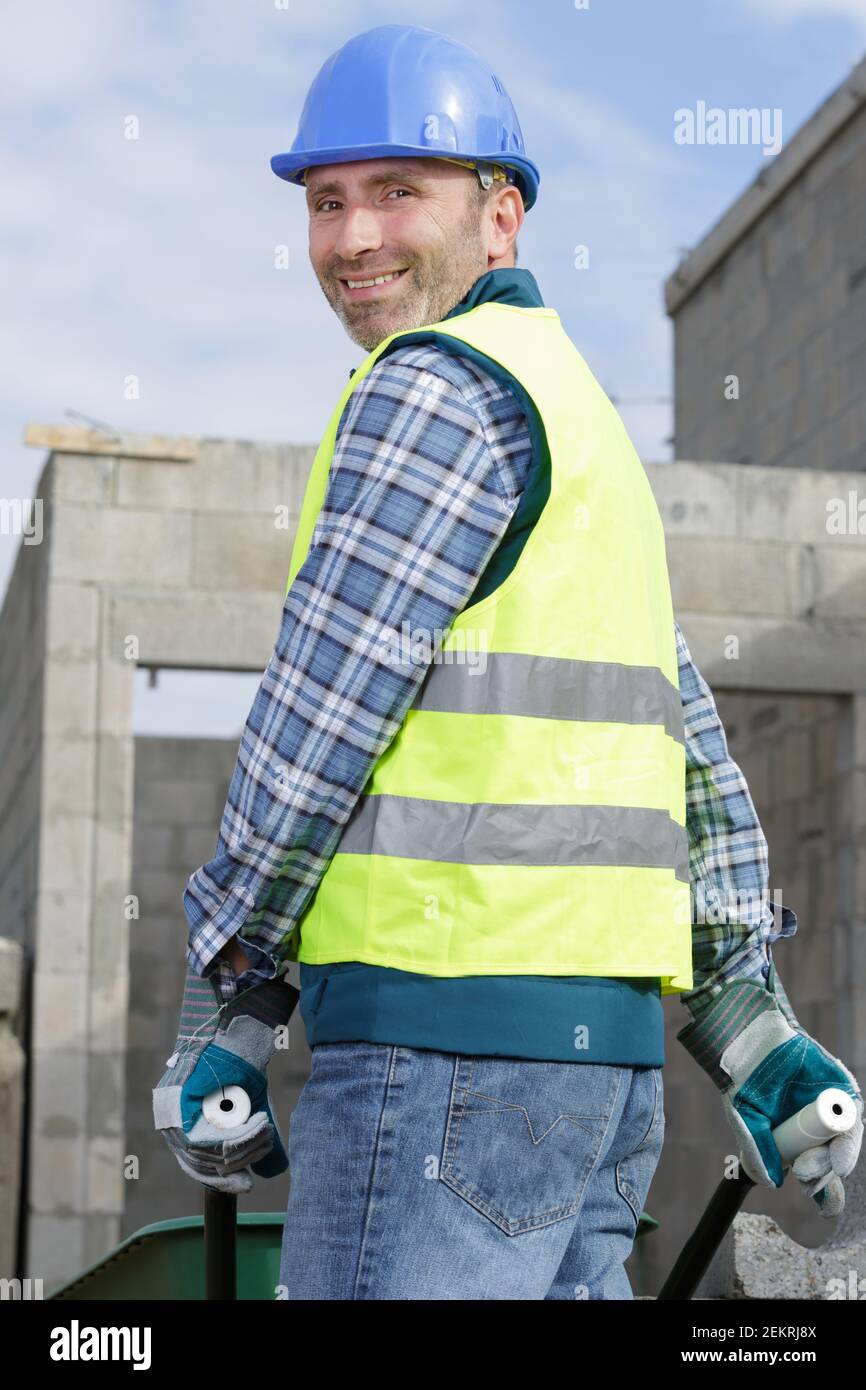 happy construction worker pushing a wheelbarrow Stock Photo