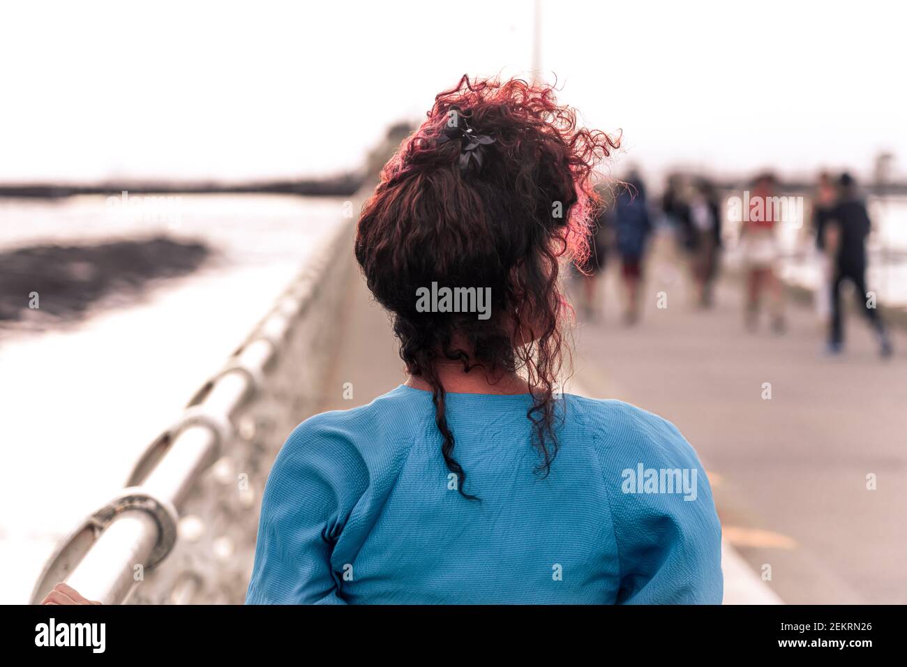 Woman in blue dress and with pink hair at sunset on St Kilda beach pier
