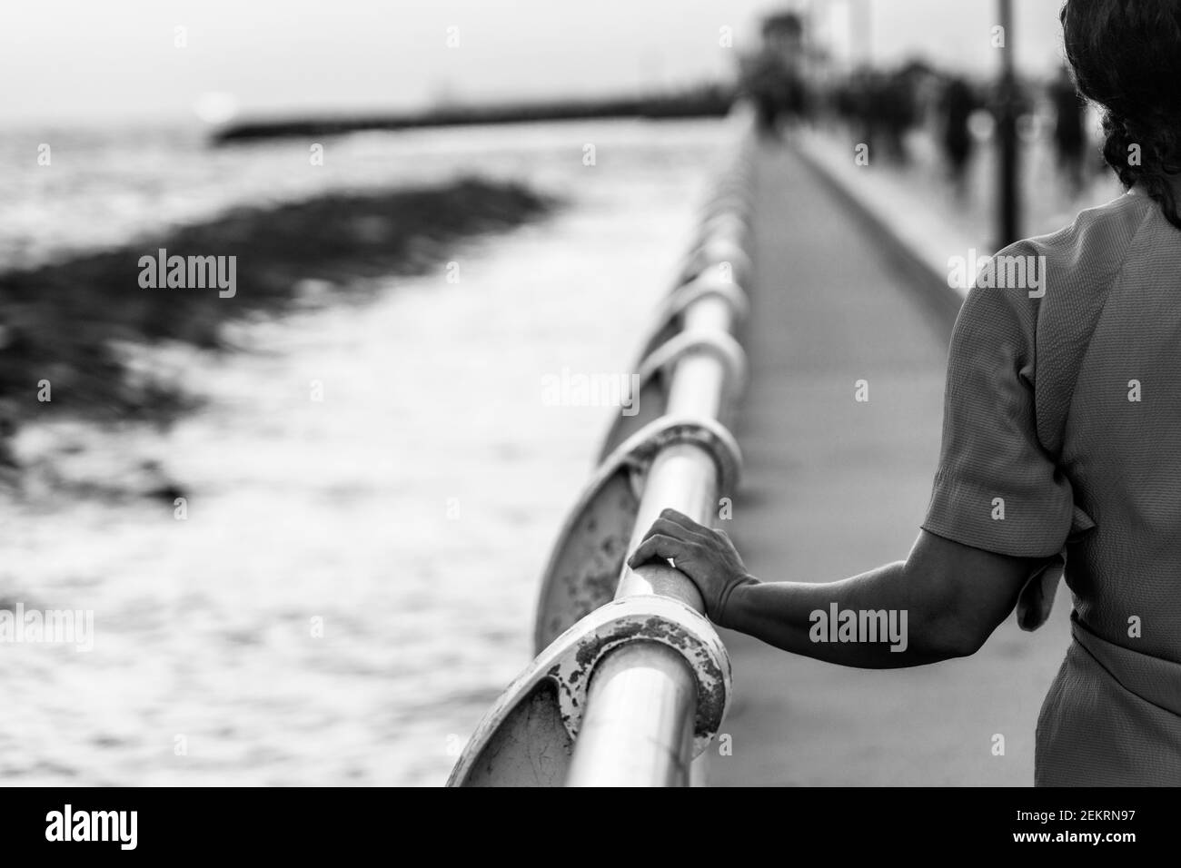 Woman in blue dress and with pink hair at sunset on St Kilda beach pier