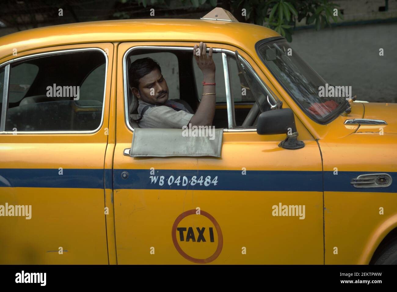 Portrait of a yellow taxi driver during a traffic congestion in Kolkata, West Bengal, India (2013).   Kolkata's yellow taxis are lately 'hardly visible on the streets' of the city, according to a publication by 'Kolkata on Wheels', a monthly motoring and lifestyle magazine. Stock Photo