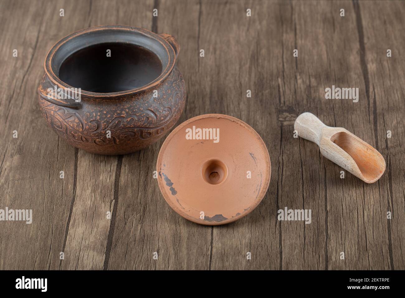Ancient pot with a wooden spoon on a wooden table Stock Photo
