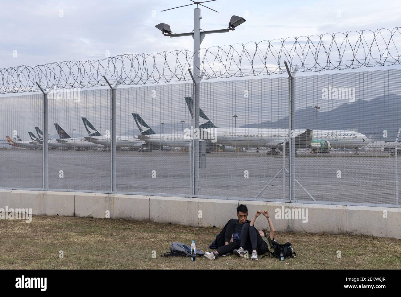 A Couple Laying Down On The Grass As Aircraft Operated By The Hong Kong Airline Cathay Pacific Airways Seen Stationed At The Hong Kong International Airport Runway Cathay Pacific A Hong Kong