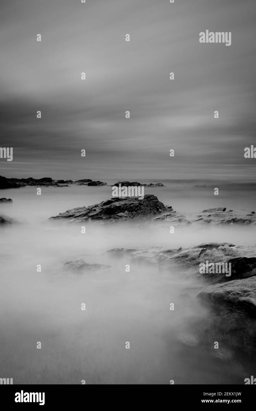 dramatic long exposure, sea rocks, rocky coastline, misty water, black and white, monochrome, b&w, serene, artistic, smooth Stock Photo