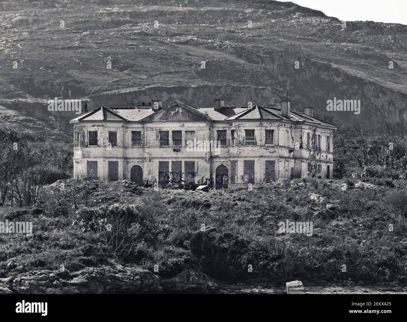 dilapidated mansion, graffiti, boarded up, disrepair, empty, abandoned, pretty ugly, once was grand, old, huge, on a hillside Stock Photo