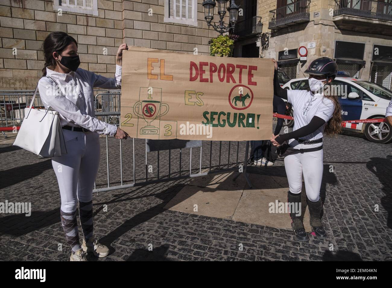 Two protesters dressed up in riding attire holding a placard saying 'sport  is safe' during the demonstration. Sports federations, gym, sports center  workers and athletes gathered in Plaza de Sant Jaume while