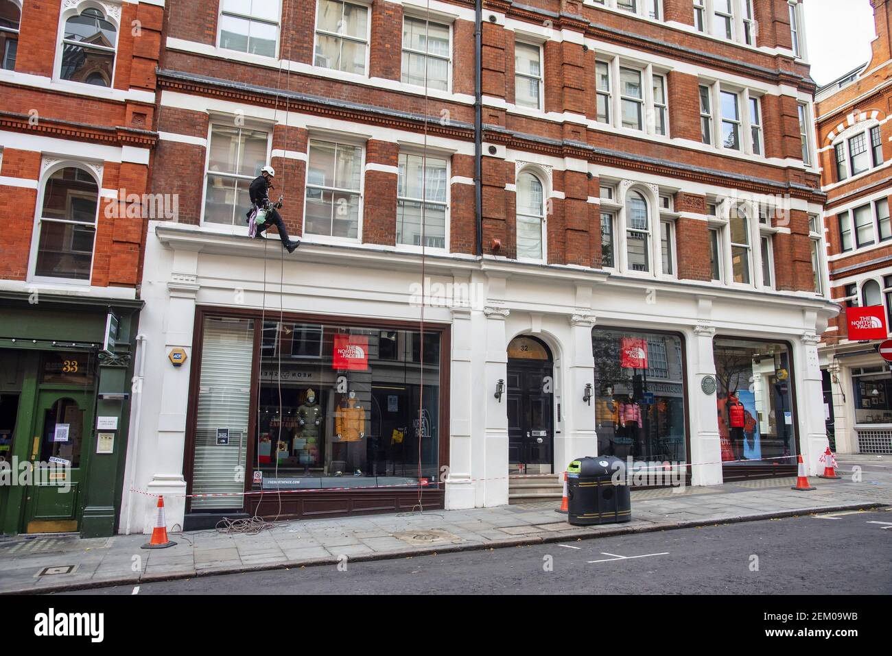 A man cleans windows above The North Face store in London?s Covent Garden  while abseiling down the side. (Photo by Dave Rushen / SOPA Images/Sipa USA  Stock Photo - Alamy