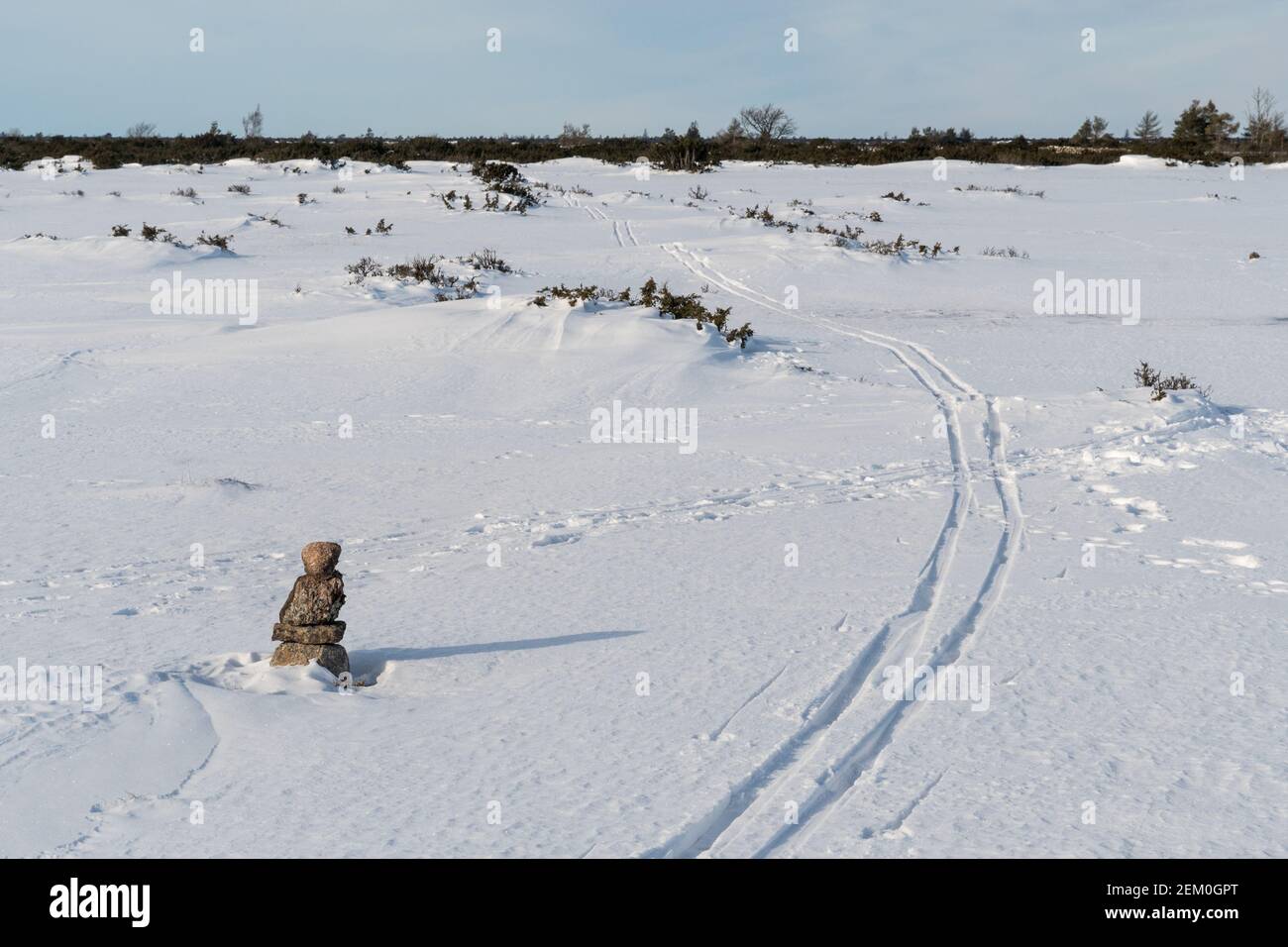 Ski tracks in a marked pathway with stone cairn Stock Photo