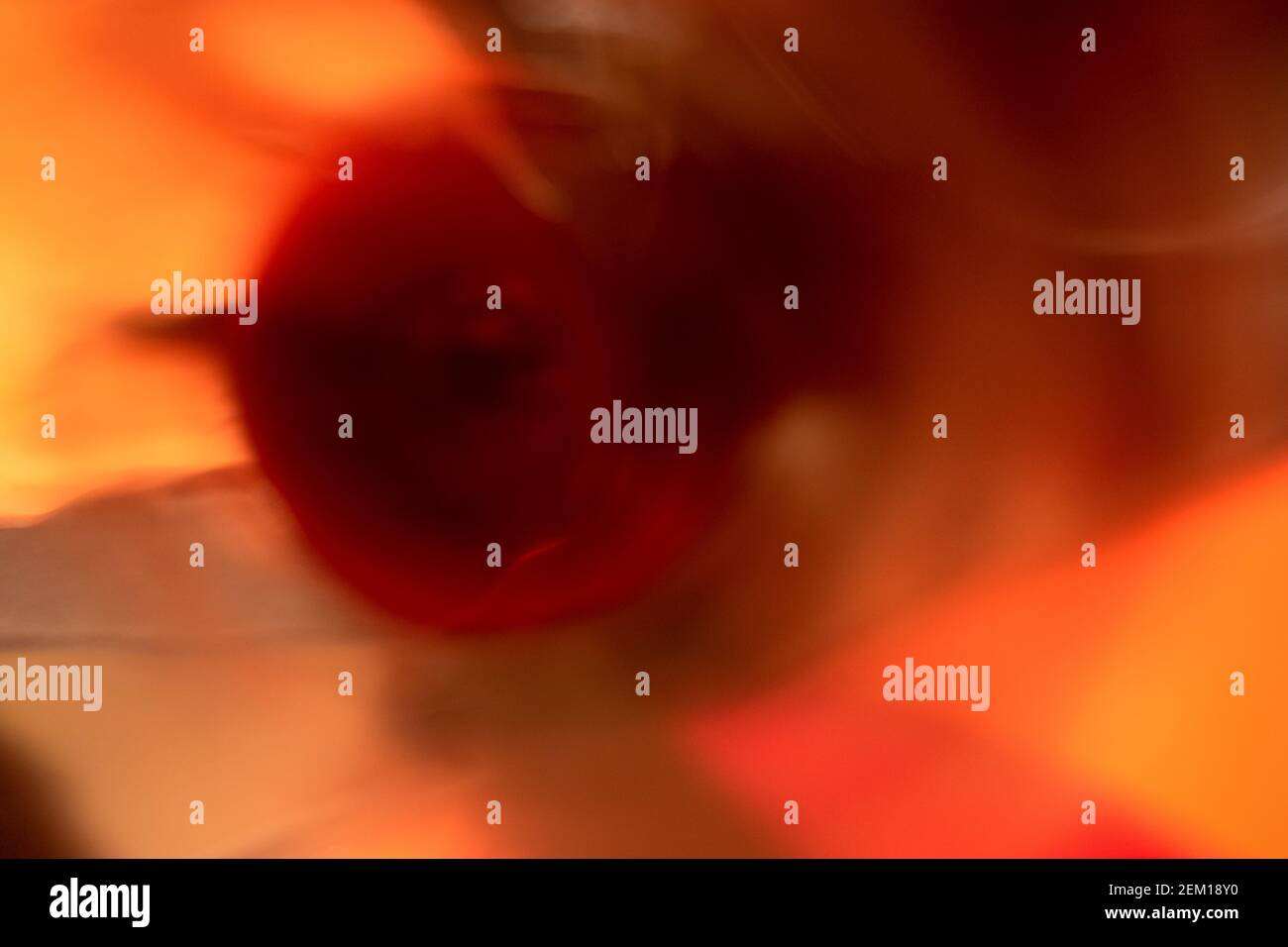 Close-up of a splash of red wine whirling, shot deep inside the glass; motion blur with red, rose, orange, yellow tinges reflected off the glass Stock Photo