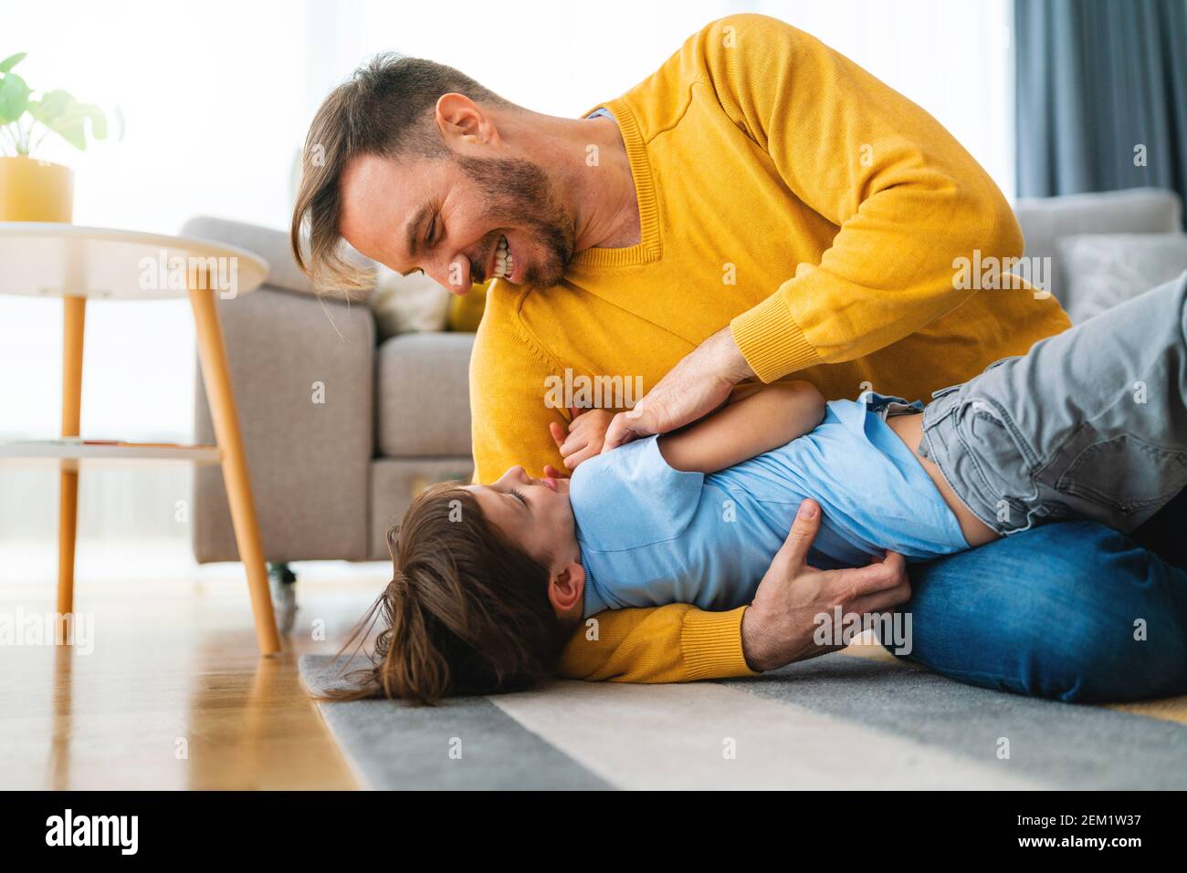 Joyful toddler boy having fun, playing with his father together at home. Stock Photo