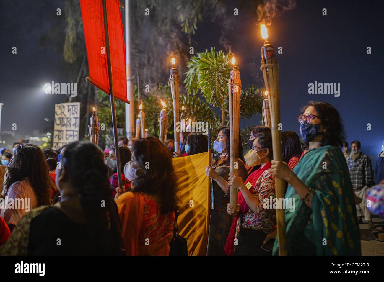 Students wearing face masks hold torches during the procession