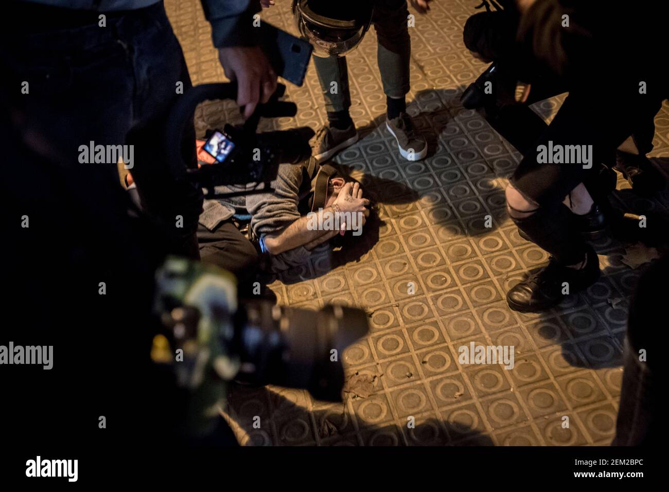 An injured journalist is on the ground surrounded by colleagues during a night of protests in support of Pablo Hasel in Barcelona. A week of protests after rapper Pablo Hasel was jailed for song lyrics and opinions on social media against Spanish monarchy. Stock Photo