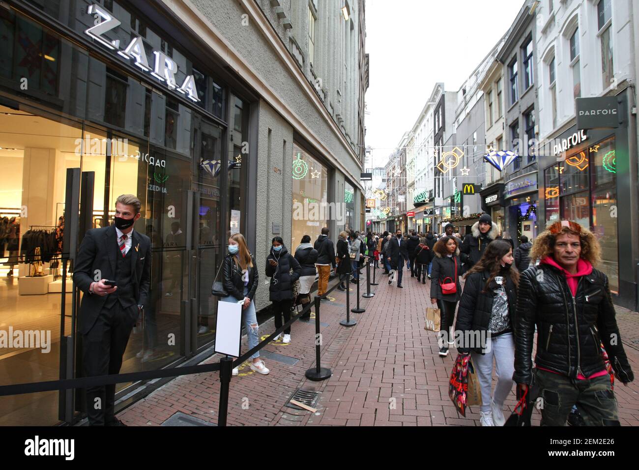 Consumers wearing protective face masks wait in line to enter in the Zara  shop during 