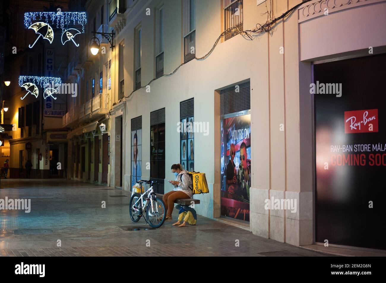 A delivery worker of Glovo sitting on a bench during the traditional