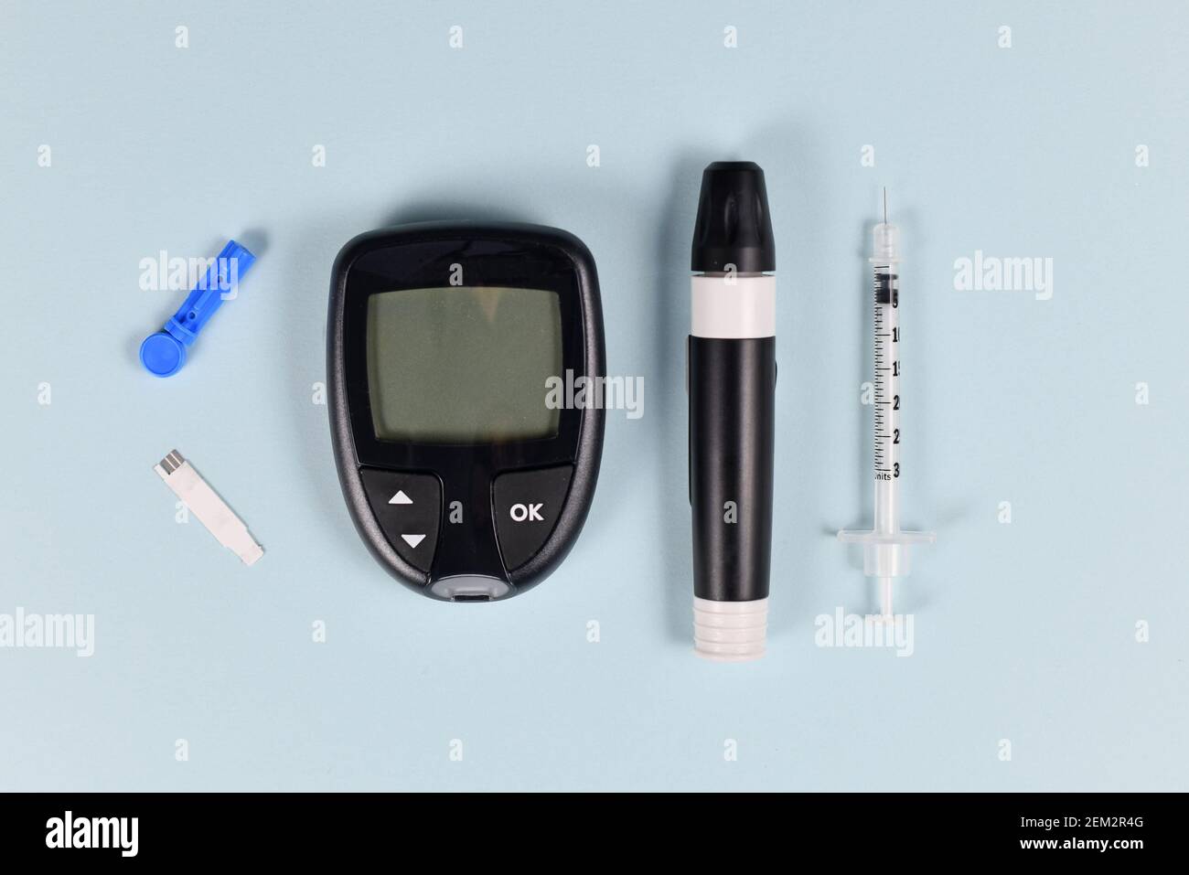 Diabetes treatment equipment with blood glucose sugar meter, lancet, syringe and lancing device on blue background Stock Photo