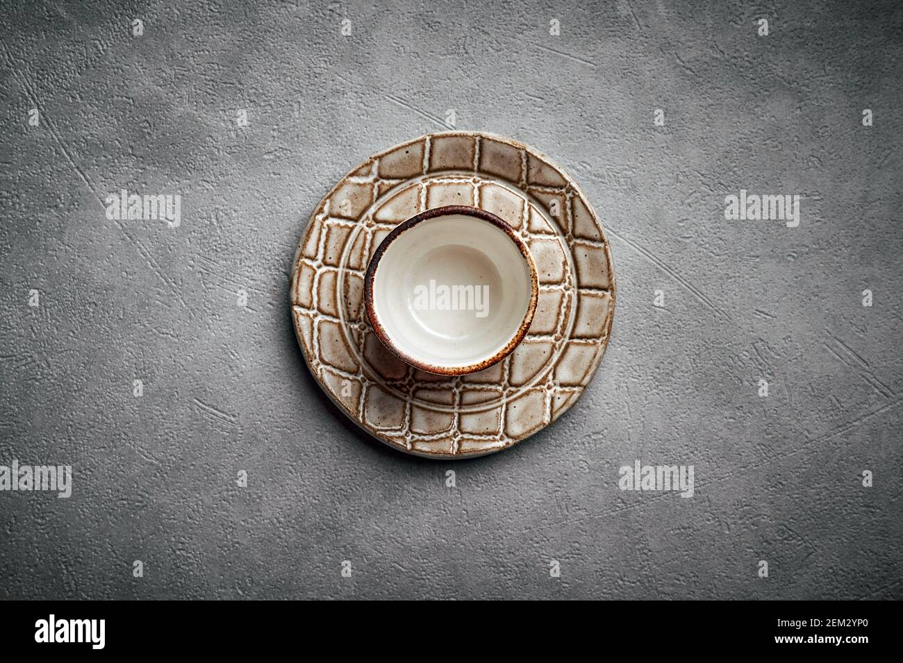Blank ceramic saucer and plate like a crocodile skin texture on a dark background, copy space, top view Stock Photo